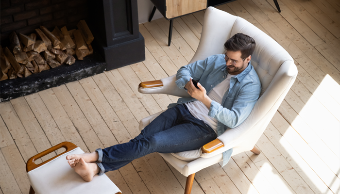 Mann von oben in einem beigen Sessel mit den Füßen auf einem Hocker